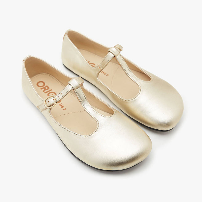 The Women's T Strap Color barefoot flat Gold in a white background 2