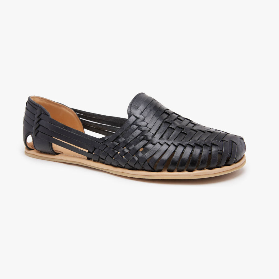 Black woven leather Huarache Slip-On Wide by Anya, angled three-quarter view of the right shoe showing the tan barefoot sole.